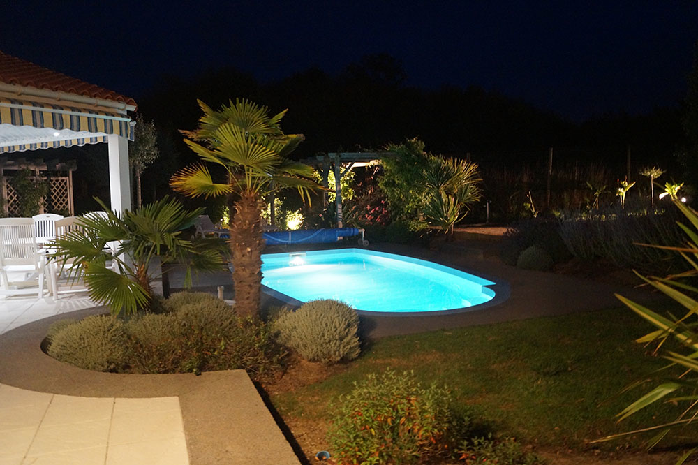 zeigt Ferienhaus mit beleuchtetem Pool bei Nacht